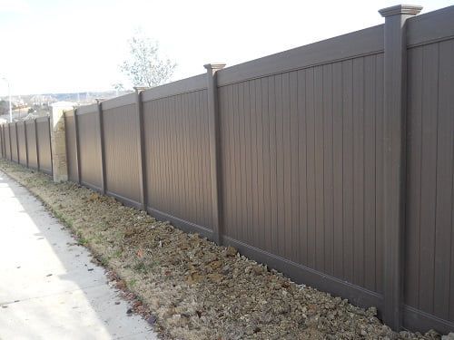 A brown fence is along the side of a road.