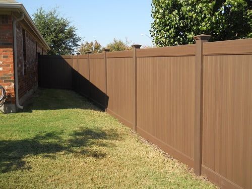 A brown wooden fence is in the backyard of a house.