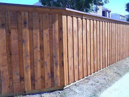 A wooden fence is sitting on the side of a road.