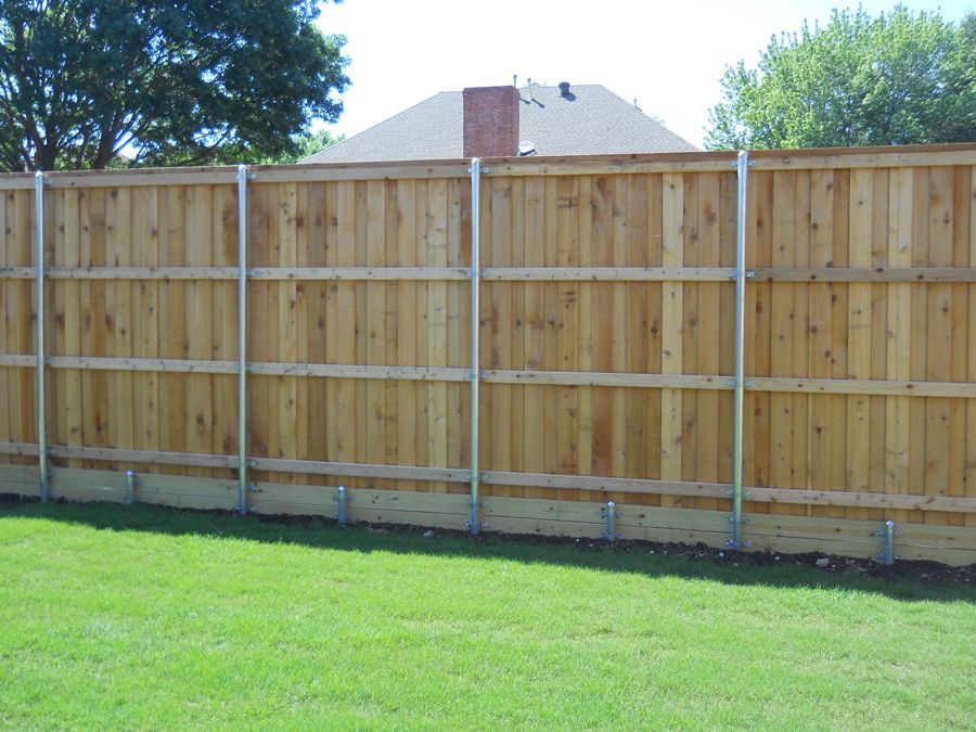 A wooden fence surrounds a lush green yard