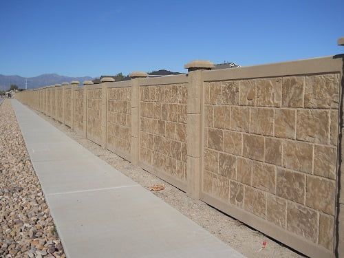 A brick fence along a sidewalk with mountains in the background
