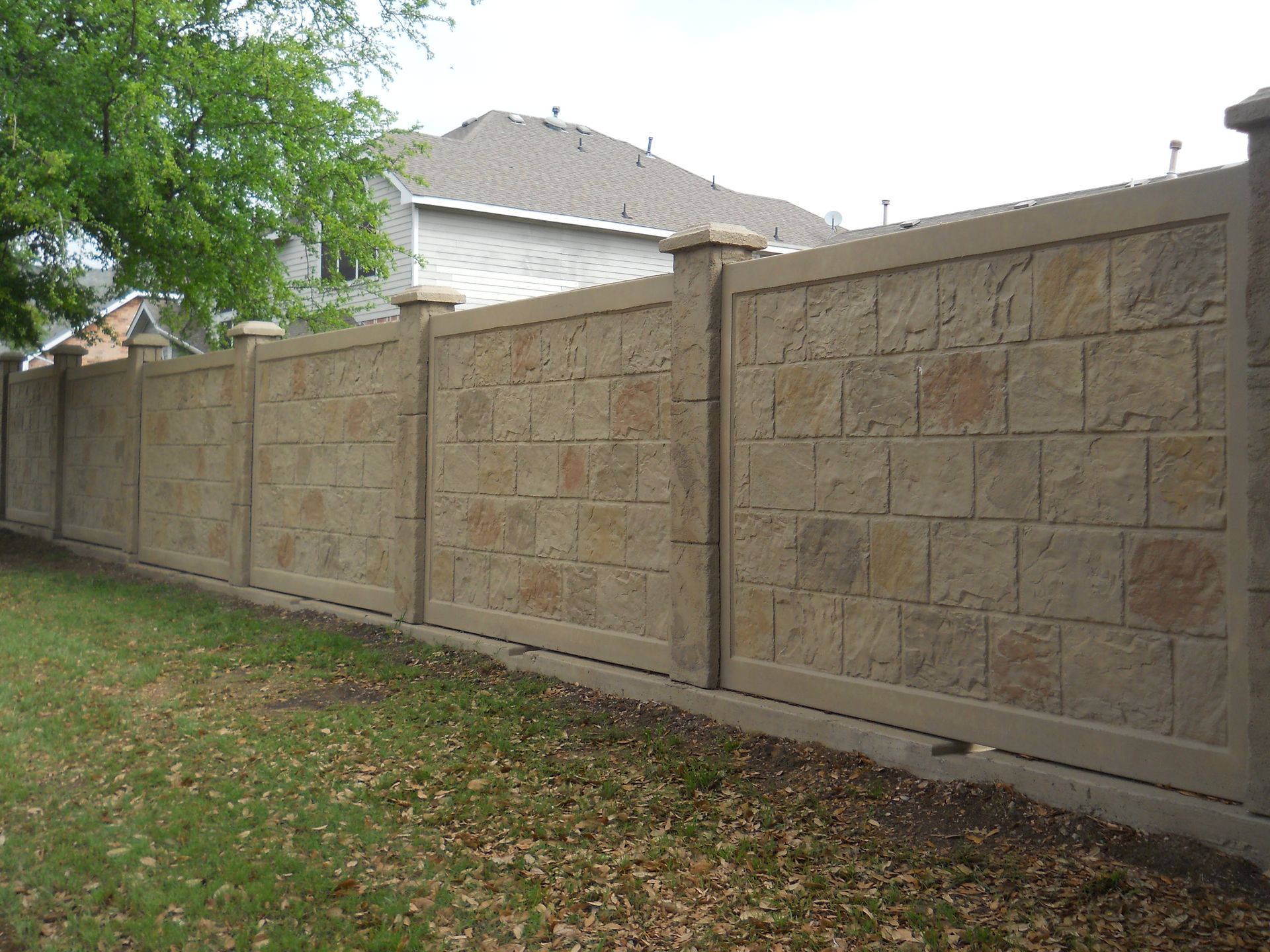 A brick fence with a house in the background