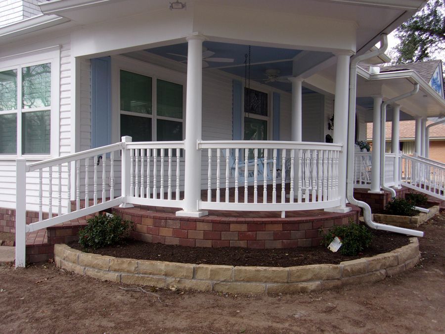 A white house with a porch with a white railing