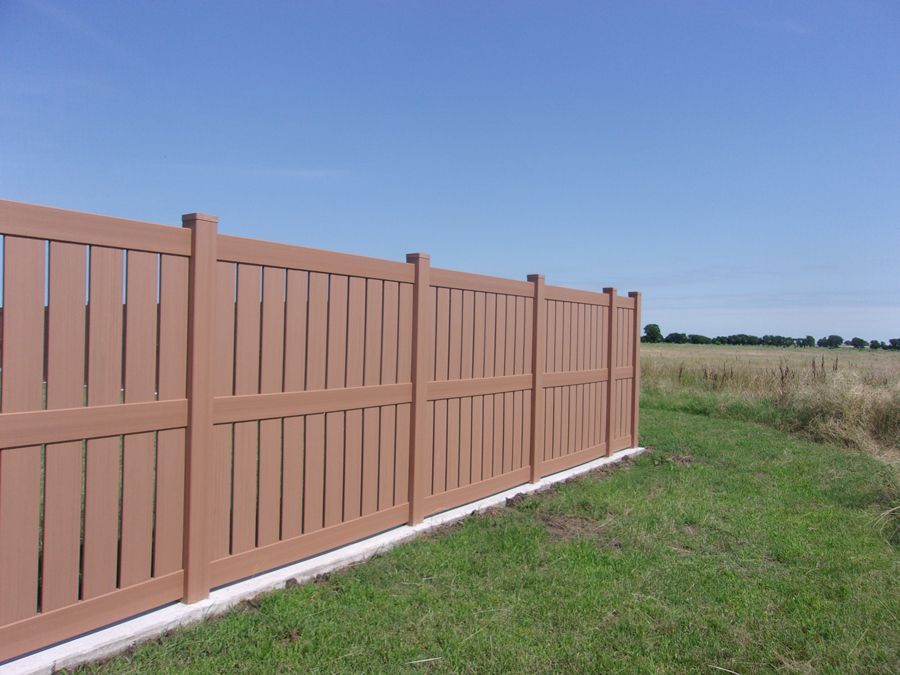 A wooden fence surrounds a grassy field with a blue sky in the background.