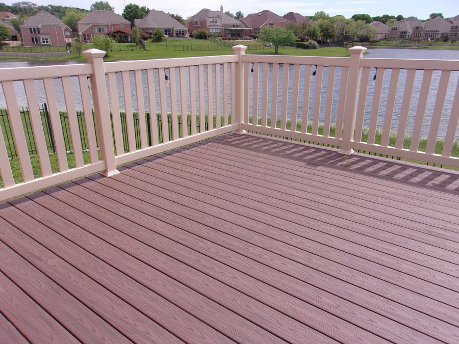 A wooden deck with a white railing overlooking a lake