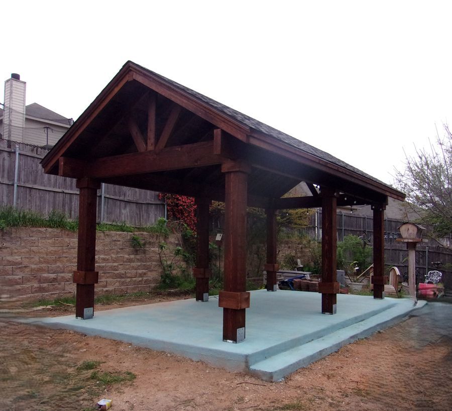 A large wooden structure with a roof is in a backyard