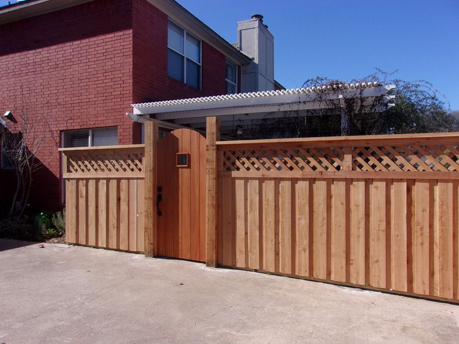 A wooden fence with a gate in front of a brick house
