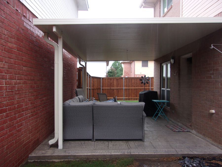 A patio with a couch and a table under a canopy.