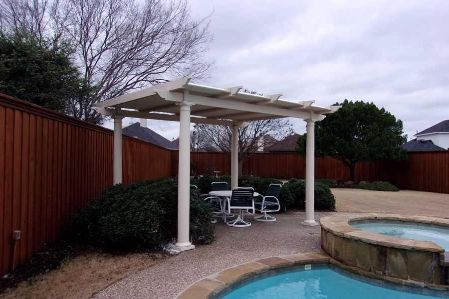 A pergola over a swimming pool with a table and chairs underneath it.
