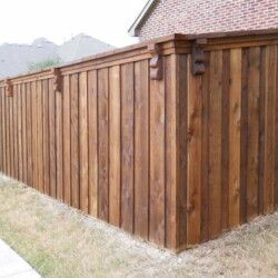 A wooden fence is sitting next to a brick house.