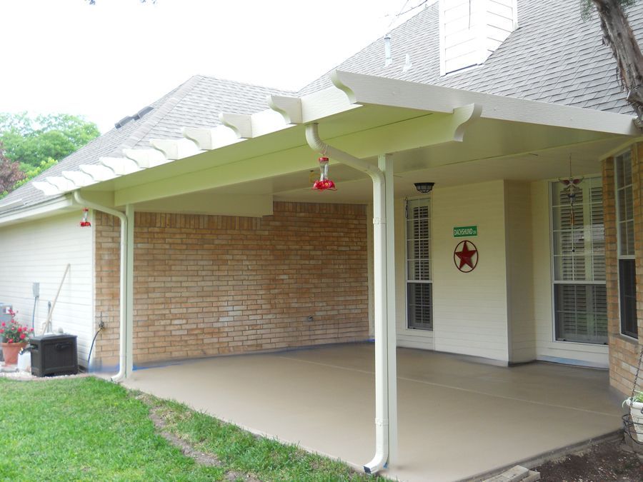 A white house with a covered patio in front of it.