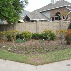 A brick fence surrounds a garden in front of a house.