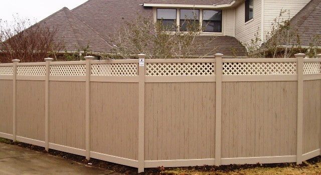 A wooden fence is in front of a house.