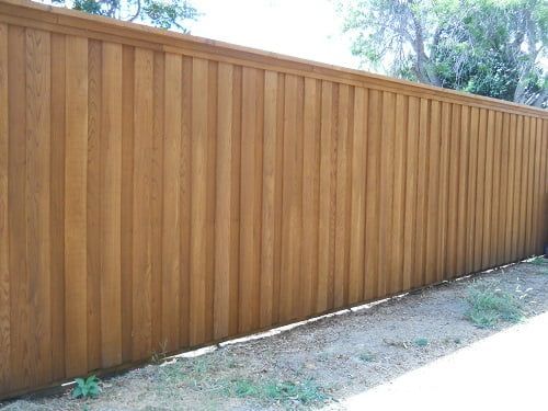 A wooden fence is sitting on top of a dirt field.