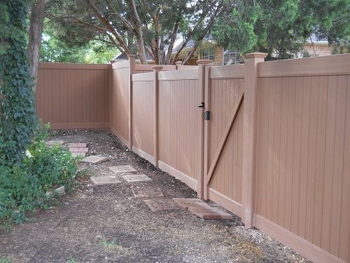 A brown wooden fence with a gate in the backyard
