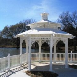 A white gazebo with a white railing overlooking a lake.
