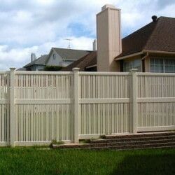 A white fence is in front of a house with a chimney.