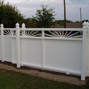 A white fence with a design on it is in a yard.