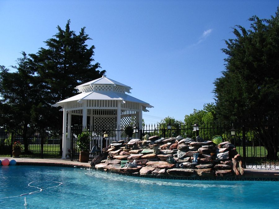 A gazebo sits next to a large swimming pool