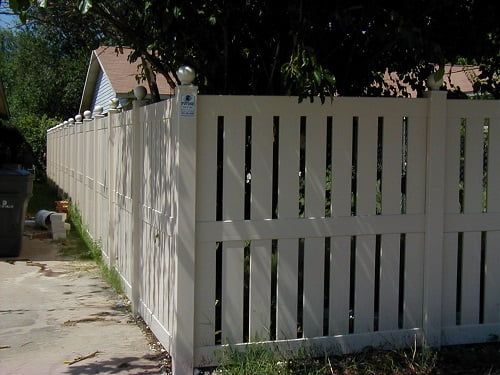 A white picket fence surrounds a driveway in front of a house