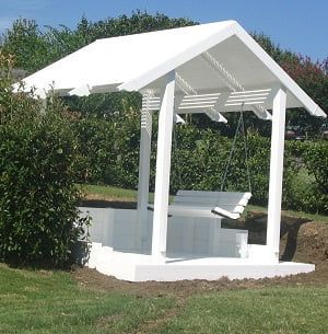 A white gazebo with a swing underneath it in a yard.