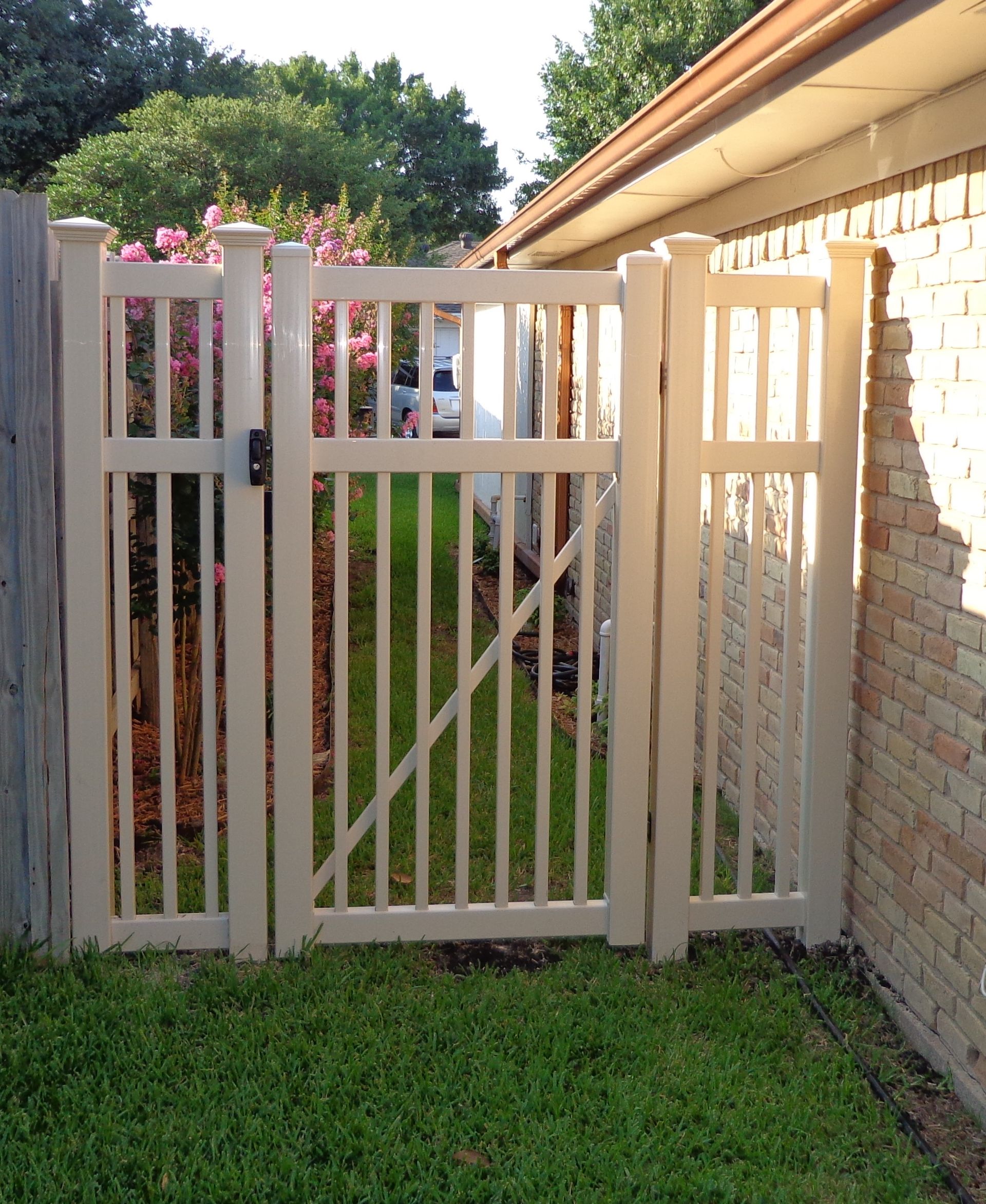 A white wooden fence with a gate in the backyard.