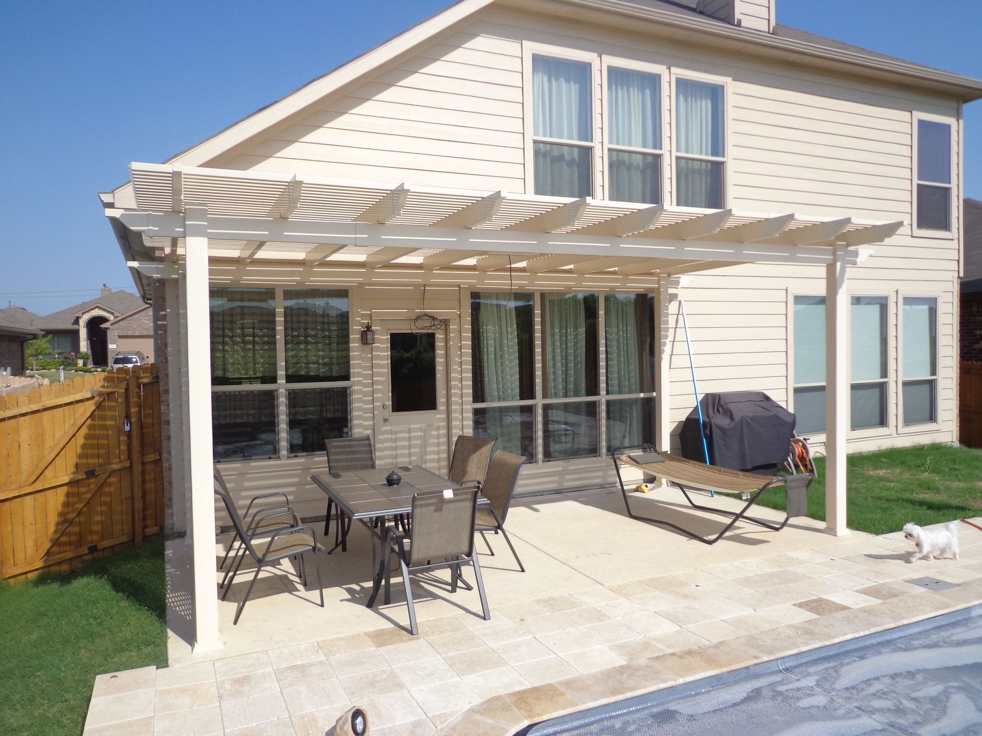 A white pergola is sitting on top of a wooden deck.