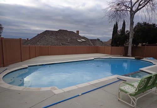 A large swimming pool is surrounded by a wooden fence.