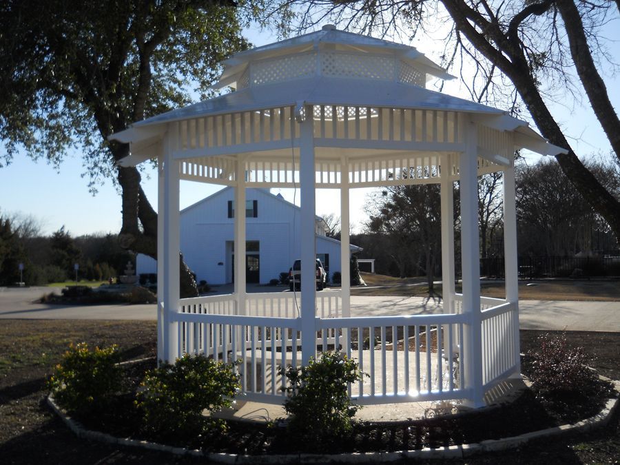 A white gazebo sits in front of a white house