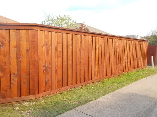 A wooden fence along a sidewalk next to a house.
