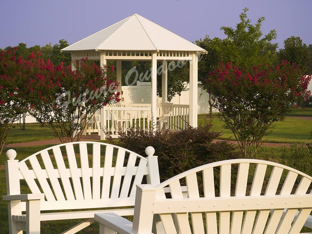 Two white benches in front of a gazebo in a park