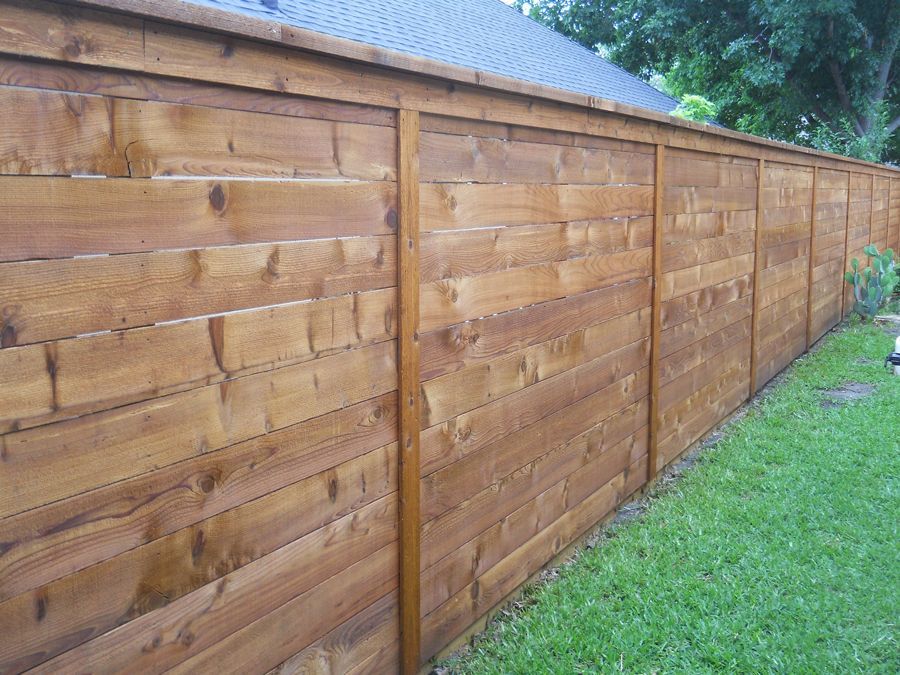 A wooden fence is sitting in the grass in front of a house.