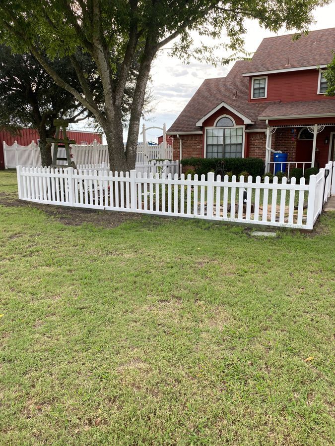 A white picket fence is in front of a red house.