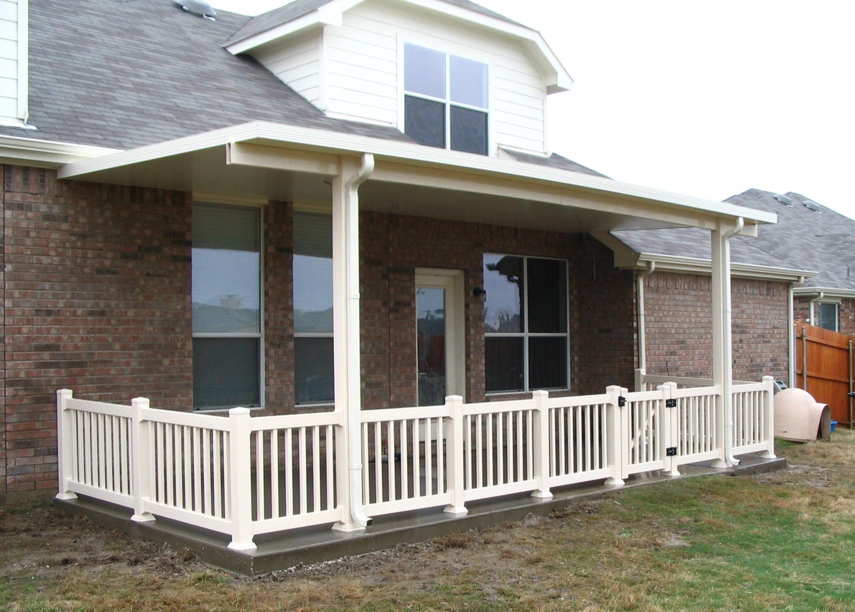 A brick house with a porch with a white railing