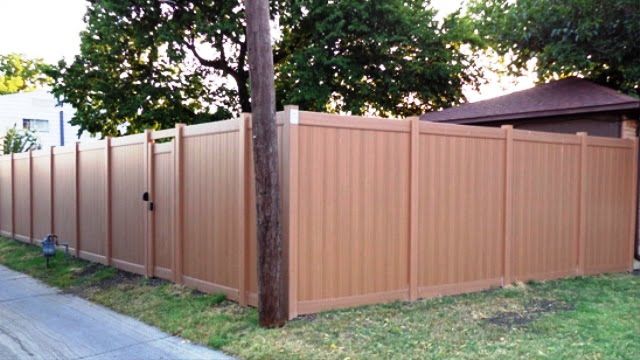 A wooden fence with a gate is surrounding a house.