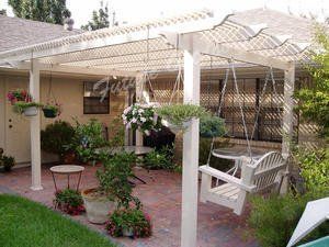 A patio with a swing , table and potted plants under a pergola.
