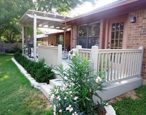 A house with a porch and a pergola in the backyard.