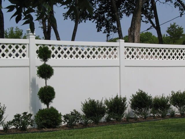 A white fence with trees in the background