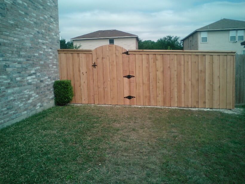 A wooden fence with a gate in the backyard of a house.