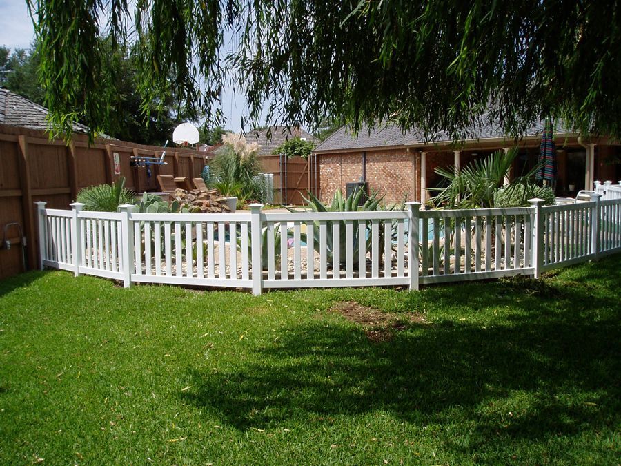A white fence surrounds a swimming pool in a backyard