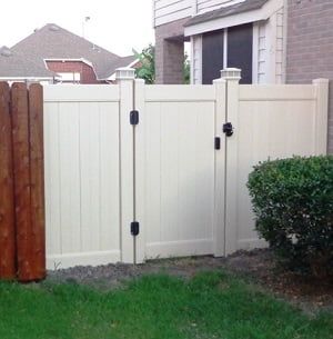 A white fence with a wooden gate in front of a house.