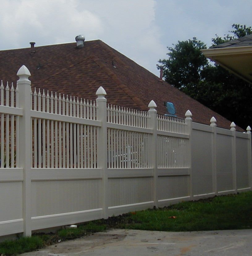 A white fence in front of a house with a red roof