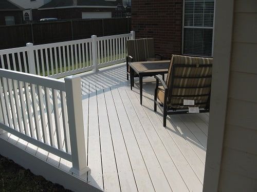 A white deck with a white railing and chairs