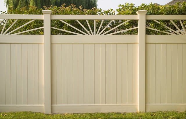 A white fence with a design on it is sitting in the grass.