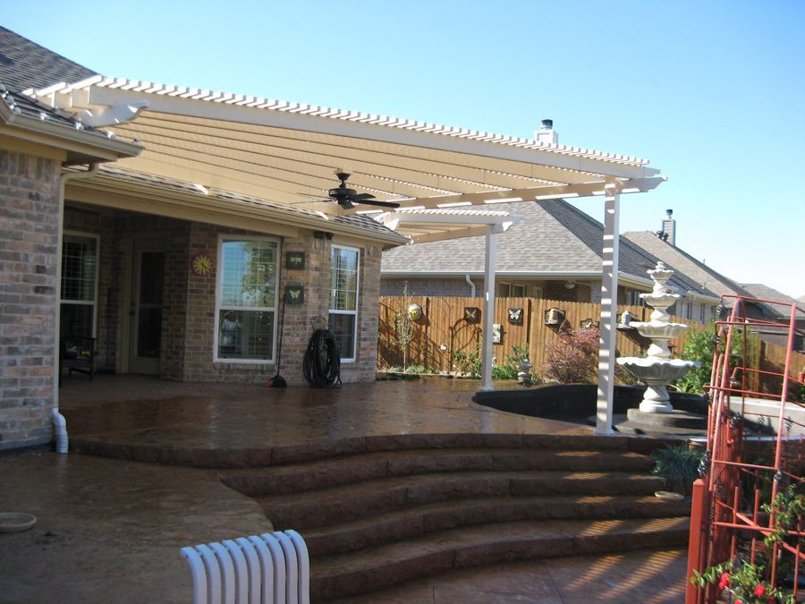 A patio with stairs and a pergola with a ceiling fan