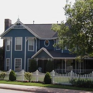 A blue house with a white picket fence around it