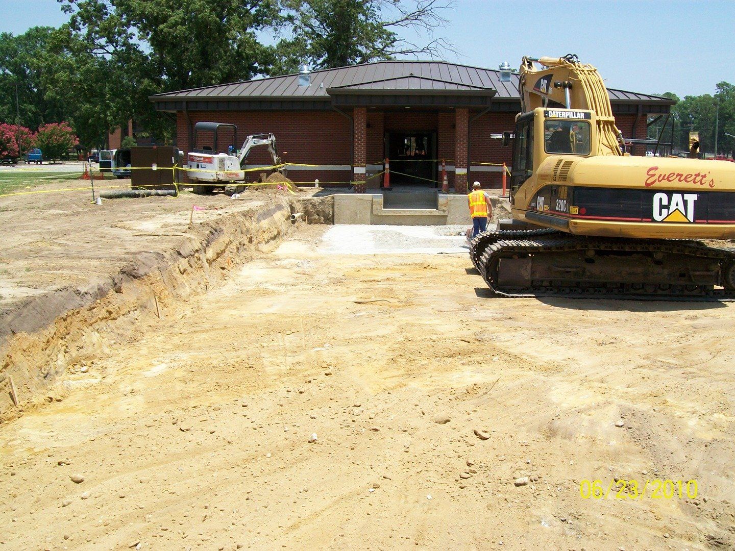 a yellow cat excavator is parked in front of a brick building