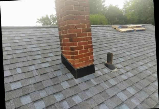 A brick chimney on top of a roof with shingles