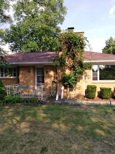 A brick house with a purple roof is surrounded by trees