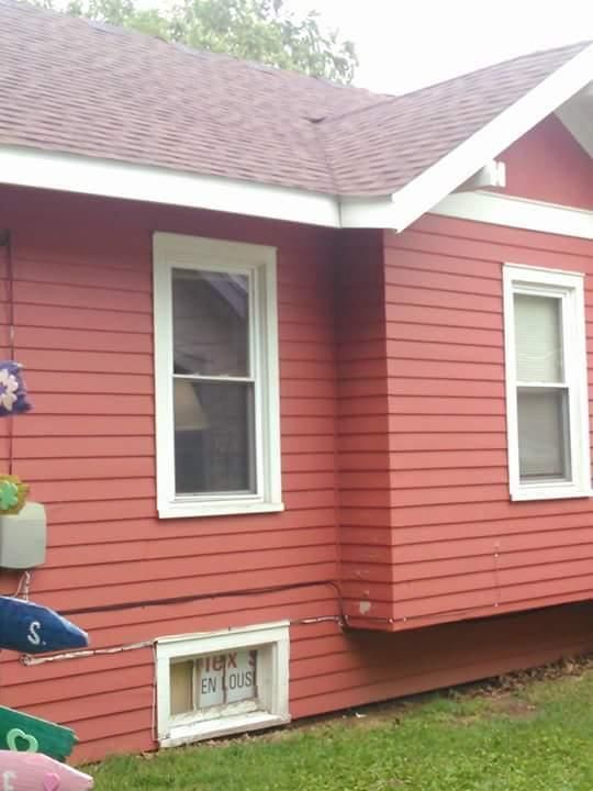 A red house with a sign on the window that says 